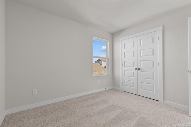 unfurnished bedroom featuring light colored carpet and a closet