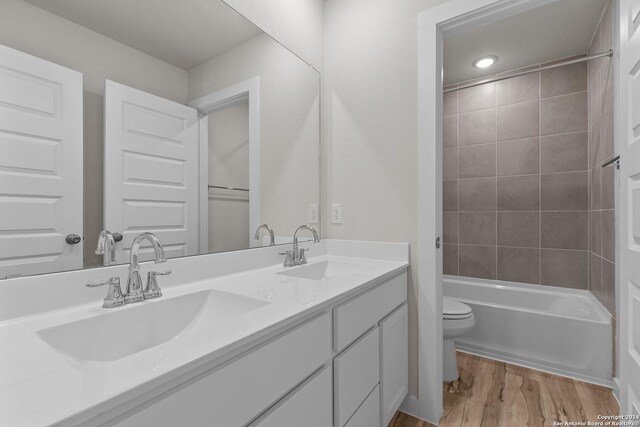 full bathroom featuring vanity, wood-type flooring, toilet, and tiled shower / bath