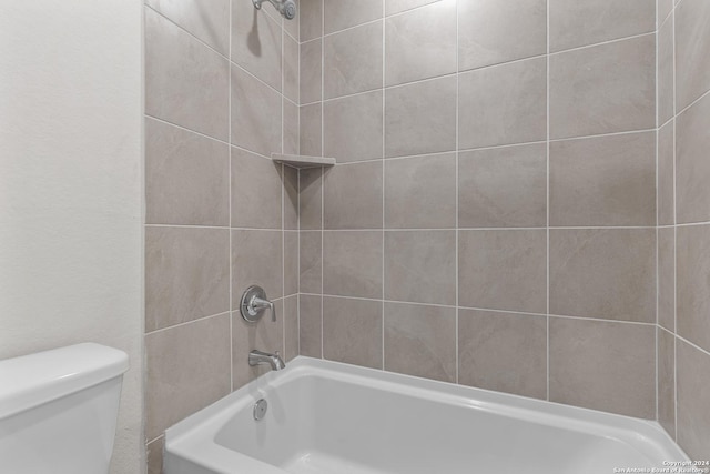 bathroom with toilet and tiled shower / bath combo
