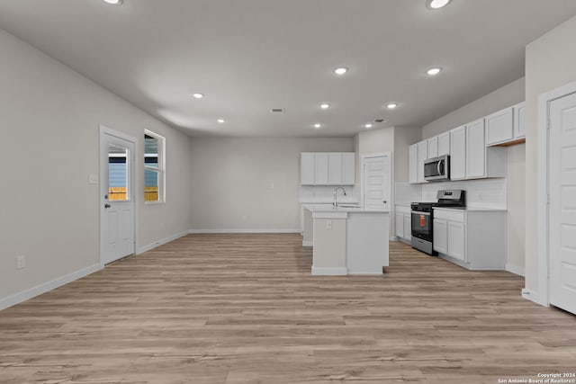 kitchen featuring white cabinetry, stainless steel appliances, sink, and an island with sink