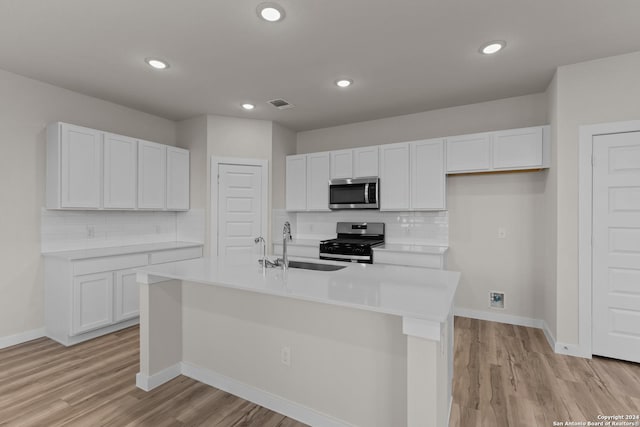 kitchen with stainless steel appliances, a kitchen island with sink, sink, and white cabinets