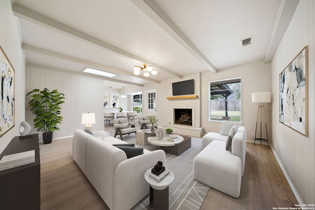 living room with a fireplace, a healthy amount of sunlight, hardwood / wood-style flooring, and beam ceiling