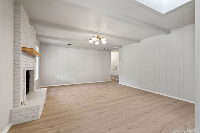 unfurnished living room featuring a brick fireplace, light hardwood / wood-style flooring, a skylight, and beamed ceiling