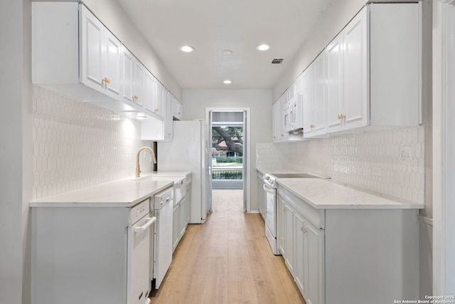 kitchen with white appliances, white cabinetry, backsplash, light wood-type flooring, and light stone counters