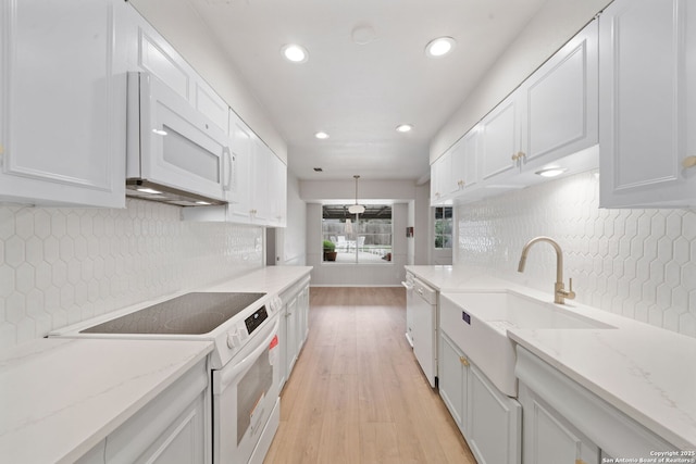 kitchen featuring white cabinetry, light stone counters, white appliances, and sink