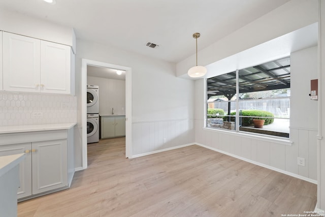 unfurnished dining area with stacked washer / dryer, light hardwood / wood-style floors, and sink