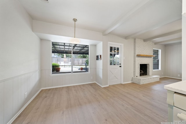 unfurnished living room featuring a brick fireplace, light hardwood / wood-style flooring, and beamed ceiling