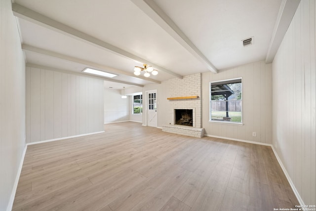 unfurnished living room with light hardwood / wood-style flooring, beam ceiling, a chandelier, and a fireplace