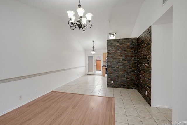 unfurnished living room featuring high vaulted ceiling, light tile patterned floors, and a notable chandelier