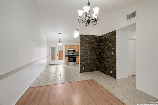 unfurnished living room with a notable chandelier, lofted ceiling, and light tile patterned flooring