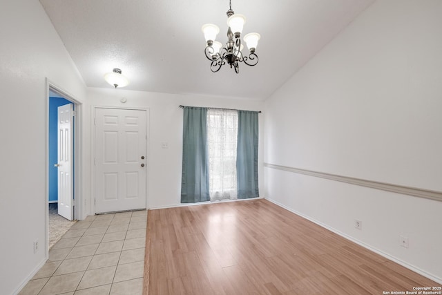 entrance foyer featuring a textured ceiling, a chandelier, light tile patterned floors, and lofted ceiling