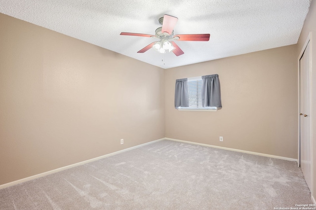 spare room featuring ceiling fan, light colored carpet, and a textured ceiling