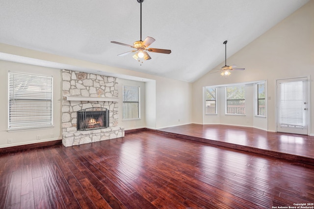 unfurnished living room with a stone fireplace, wood-type flooring, ceiling fan, and vaulted ceiling