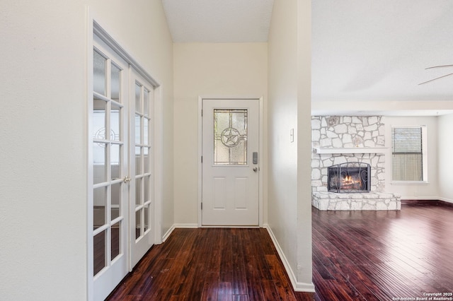 doorway with hardwood / wood-style flooring, a stone fireplace, and a textured ceiling