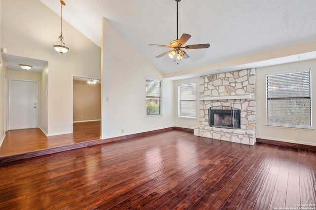 unfurnished living room featuring lofted ceiling, dark wood-type flooring, a fireplace, and ceiling fan