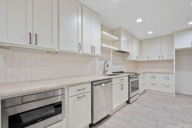 kitchen with light stone counters, tasteful backsplash, white cabinets, and appliances with stainless steel finishes