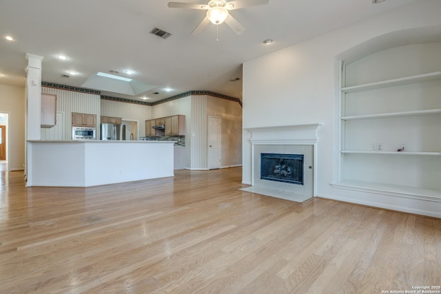 unfurnished living room featuring a fireplace, light hardwood / wood-style flooring, and ceiling fan