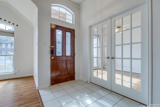 entrance foyer featuring plenty of natural light, light tile patterned floors, ornamental molding, and french doors