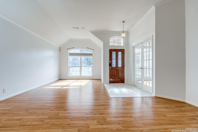 foyer featuring crown molding, light hardwood / wood-style flooring, lofted ceiling, and french doors