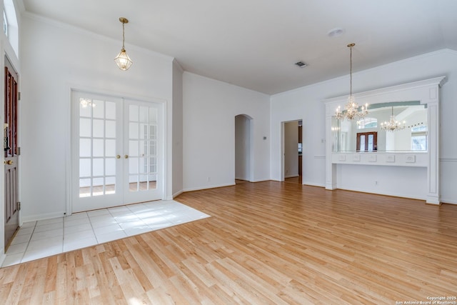 unfurnished living room with a notable chandelier, french doors, and light hardwood / wood-style flooring