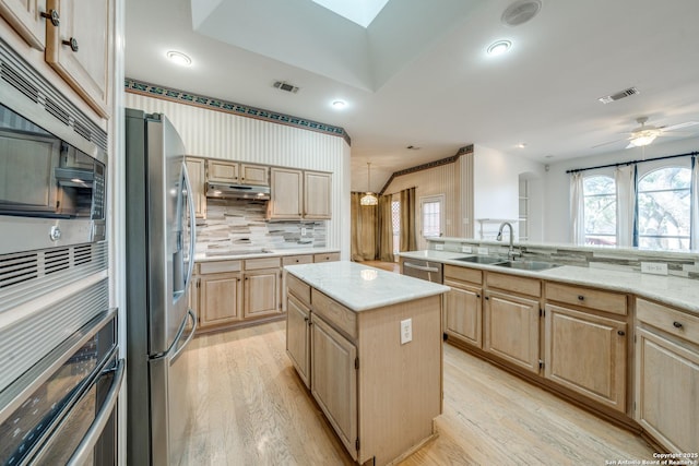 kitchen with light brown cabinetry, sink, a center island, light hardwood / wood-style floors, and stainless steel appliances