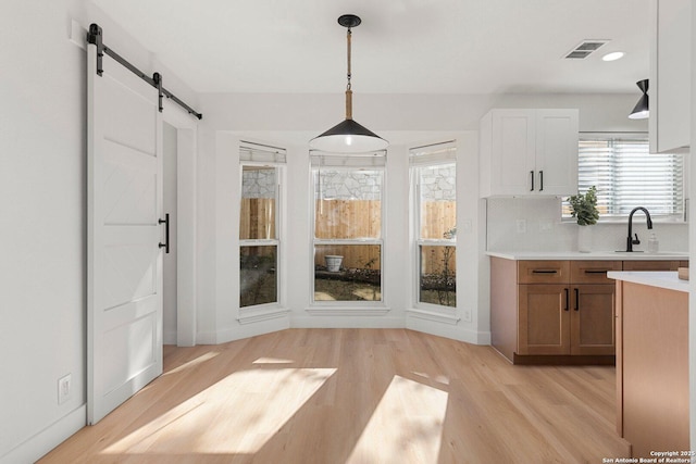 unfurnished dining area featuring a barn door, sink, and light wood-type flooring