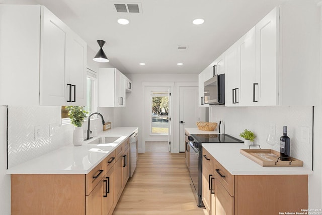 kitchen featuring white cabinetry, sink, light wood-type flooring, and appliances with stainless steel finishes