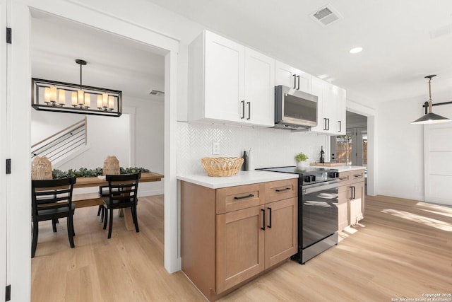 kitchen featuring appliances with stainless steel finishes, light wood-type flooring, hanging light fixtures, and white cabinets