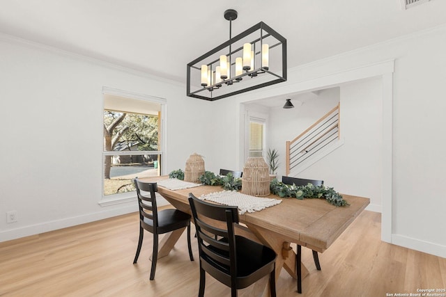 dining area featuring crown molding, a notable chandelier, and light wood-type flooring