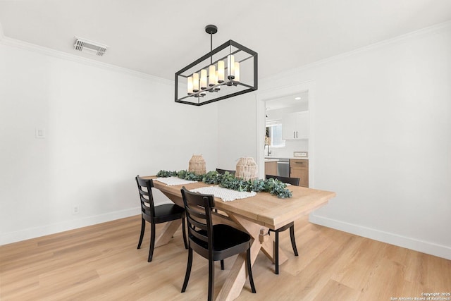 dining room with a notable chandelier, crown molding, and light hardwood / wood-style floors