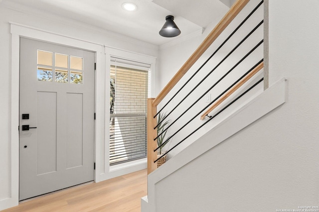 foyer entrance featuring crown molding, a wealth of natural light, and light hardwood / wood-style floors