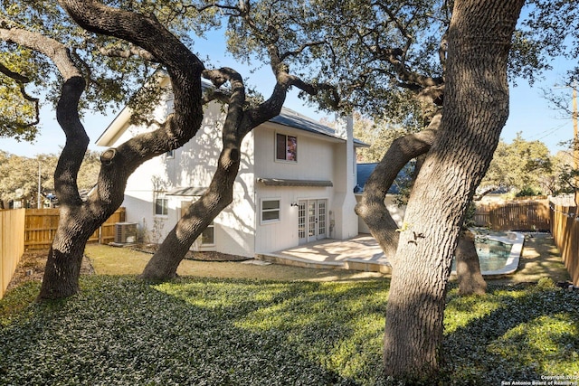 rear view of property with french doors, cooling unit, and a lawn