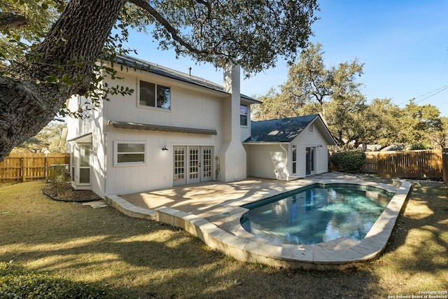 rear view of house with a fenced in pool, a lawn, french doors, and a patio area