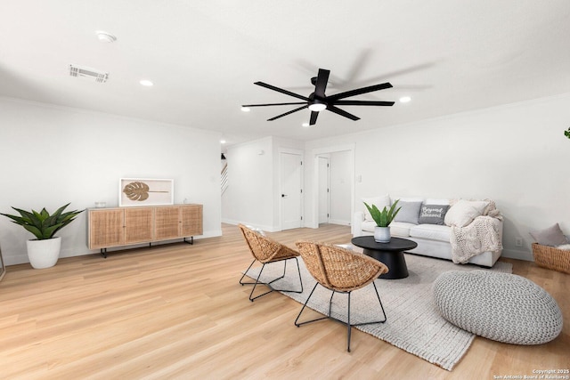 living room with light hardwood / wood-style flooring, ornamental molding, and ceiling fan