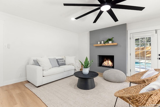 living room featuring light hardwood / wood-style flooring, a large fireplace, and ceiling fan