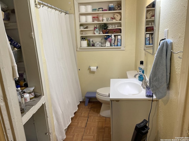 bathroom featuring toilet, vanity, and parquet flooring