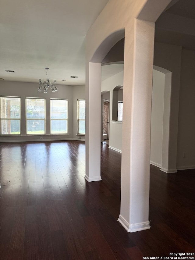 unfurnished room with an inviting chandelier and dark hardwood / wood-style flooring