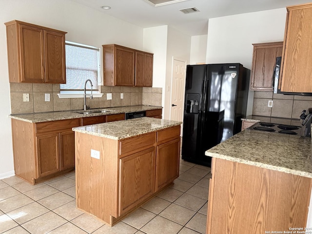 kitchen with sink, light tile patterned floors, black appliances, and a kitchen island