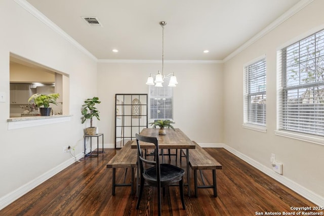 dining area featuring dark hardwood / wood-style flooring, an inviting chandelier, and ornamental molding