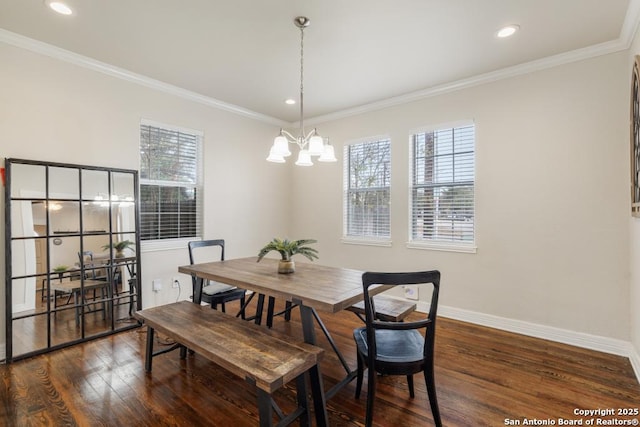 dining space with dark wood-type flooring, ornamental molding, and a notable chandelier