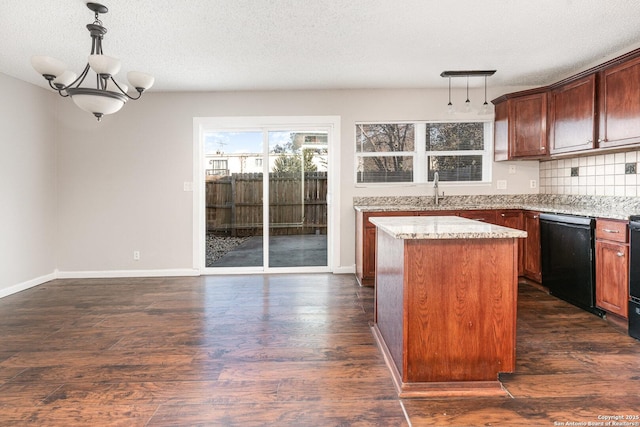 kitchen featuring pendant lighting, a textured ceiling, a kitchen island, black dishwasher, and backsplash