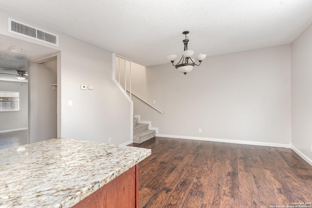 kitchen with ceiling fan with notable chandelier, dark wood-type flooring, a textured ceiling, and pendant lighting