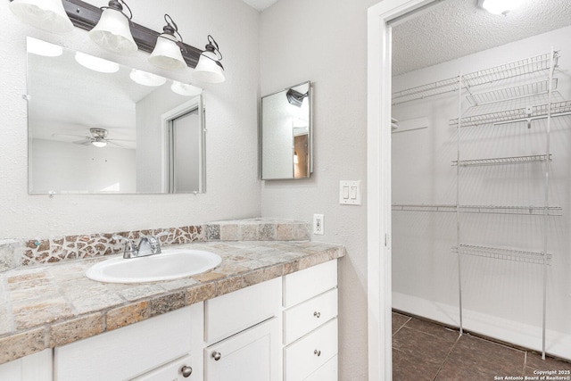 bathroom with ceiling fan, a textured ceiling, tile patterned floors, and vanity