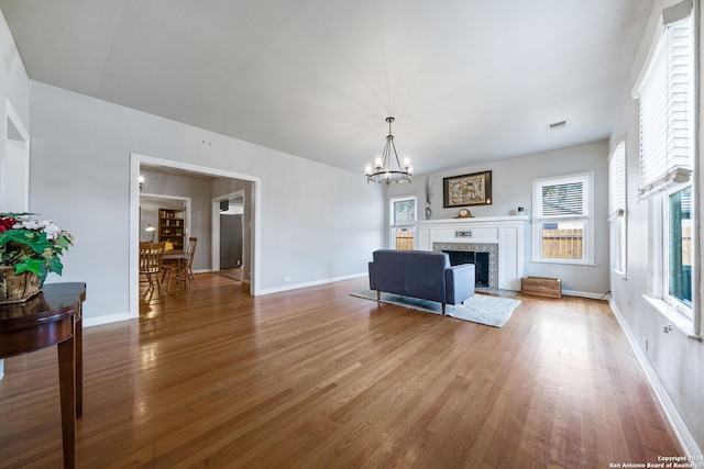 living room with hardwood / wood-style flooring, an inviting chandelier, and a fireplace