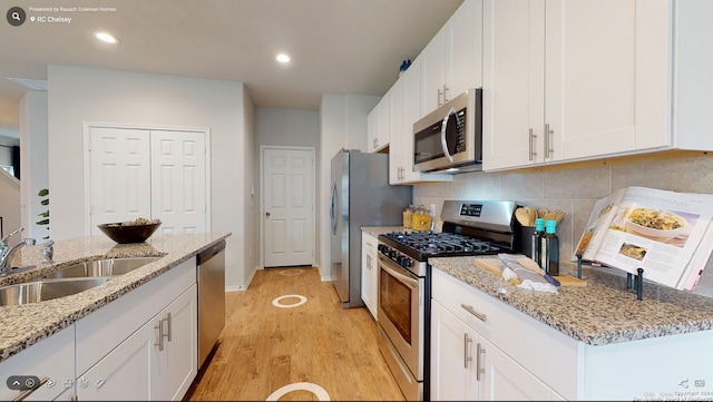 kitchen with light stone countertops, appliances with stainless steel finishes, tasteful backsplash, white cabinetry, and sink