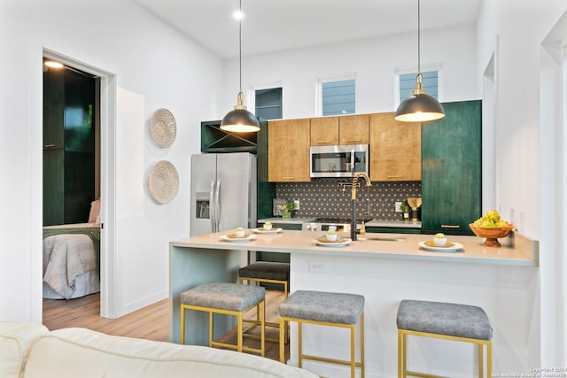 kitchen featuring tasteful backsplash, a breakfast bar, hanging light fixtures, and stainless steel appliances