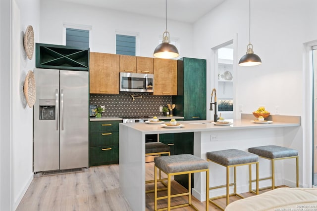 kitchen with a kitchen bar, stainless steel appliances, decorative backsplash, light hardwood / wood-style floors, and sink