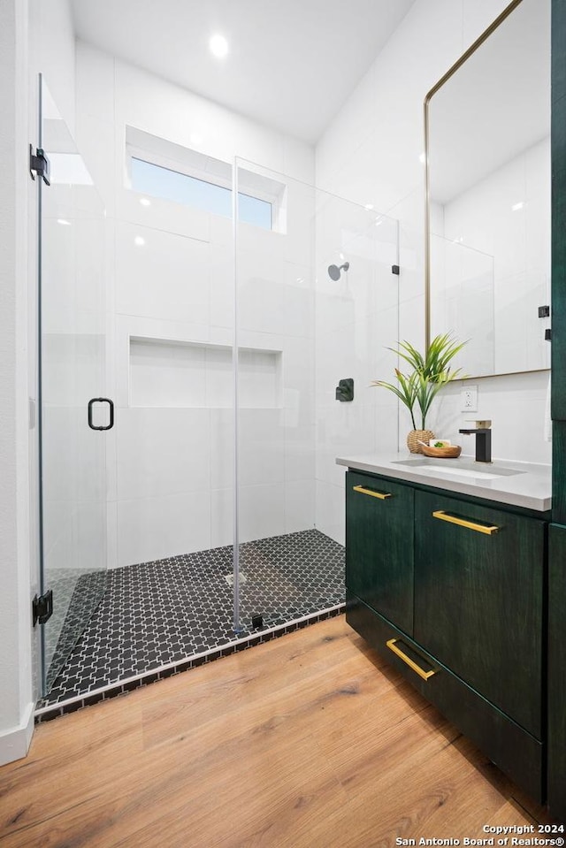 bathroom with hardwood / wood-style floors, walk in shower, and vanity