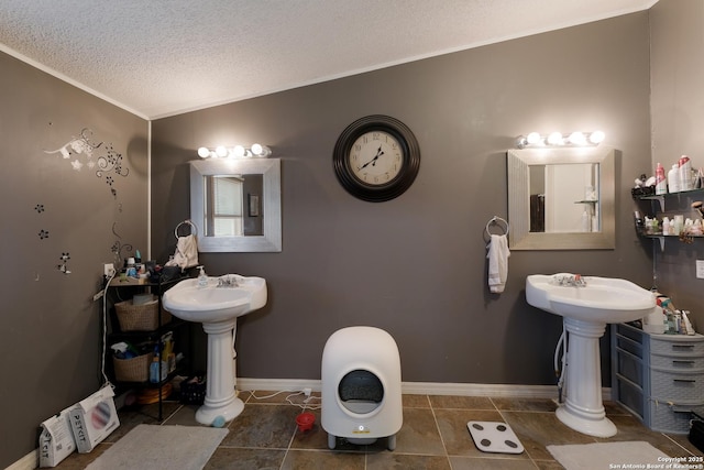 bathroom with double sink, tile patterned floors, a textured ceiling, and crown molding