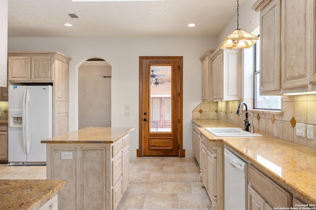 kitchen with white appliances, light brown cabinetry, sink, backsplash, and hanging light fixtures